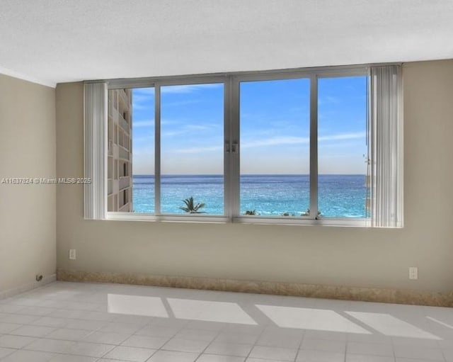 tiled empty room with a textured ceiling and a water view