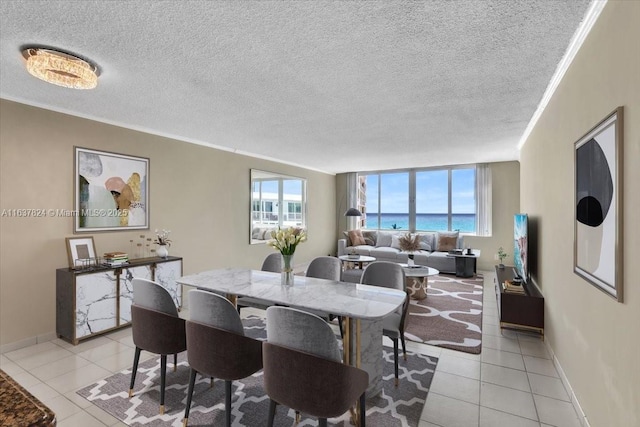 dining space with a textured ceiling, light tile patterned floors, plenty of natural light, and ornamental molding