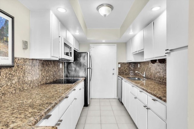 kitchen featuring sink, white cabinetry, backsplash, dark stone countertops, and black electric stovetop