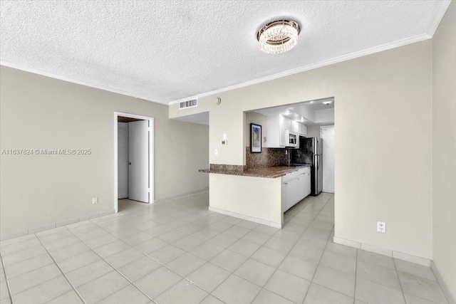 kitchen with white cabinetry, a textured ceiling, appliances with stainless steel finishes, kitchen peninsula, and decorative backsplash