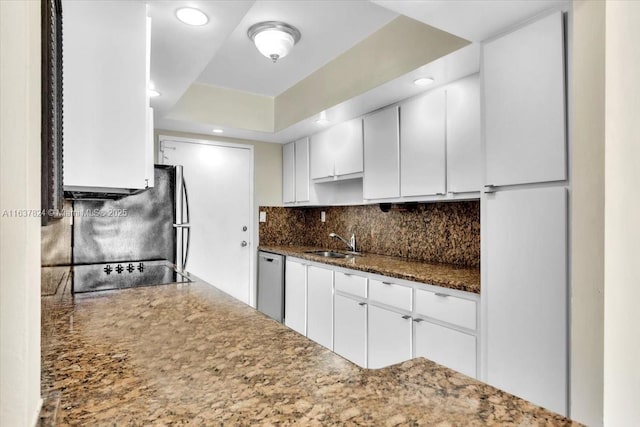 kitchen with sink, tasteful backsplash, dark stone countertops, dishwasher, and white cabinets