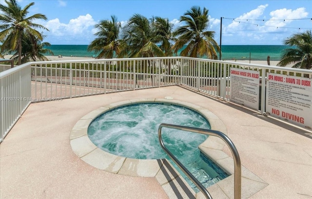 view of pool featuring a water view and a hot tub