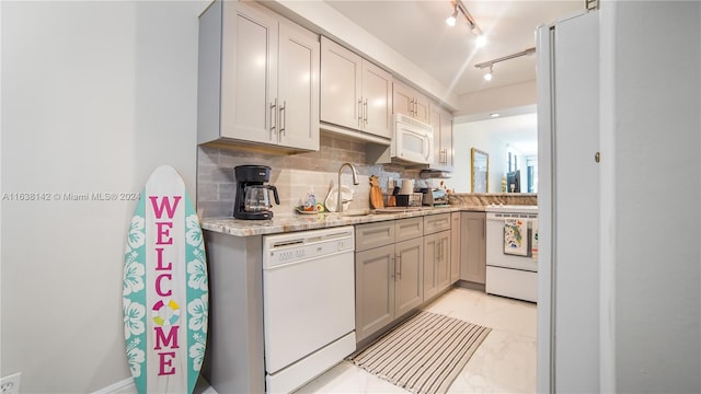 kitchen featuring decorative backsplash, rail lighting, light tile patterned floors, gray cabinetry, and white appliances