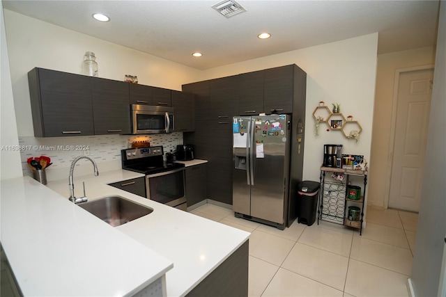 kitchen featuring kitchen peninsula, sink, decorative backsplash, appliances with stainless steel finishes, and light tile patterned flooring