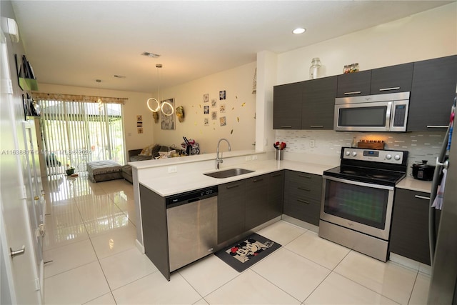 kitchen featuring light tile patterned floors, stainless steel appliances, sink, kitchen peninsula, and pendant lighting