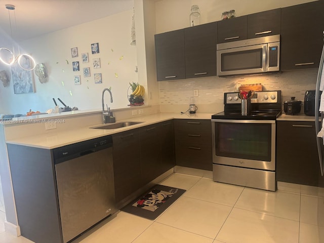 kitchen with pendant lighting, appliances with stainless steel finishes, tasteful backsplash, sink, and light tile patterned flooring