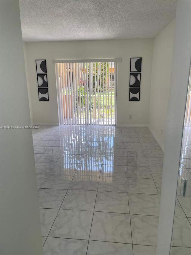 spare room with a textured ceiling and light tile patterned floors