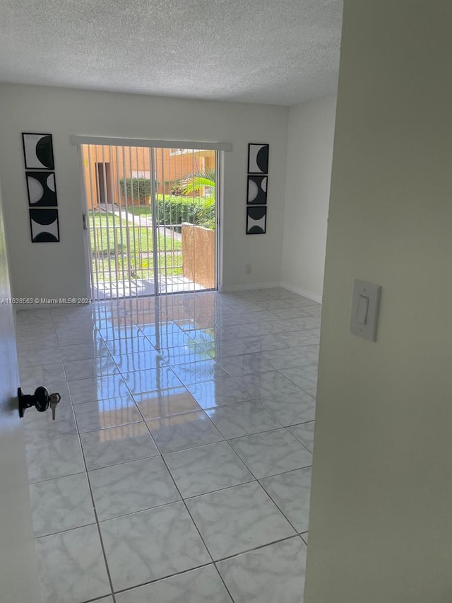 unfurnished room with light tile patterned floors and a textured ceiling