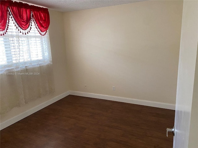 empty room with dark hardwood / wood-style flooring and a textured ceiling