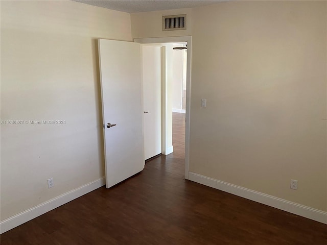 empty room featuring a textured ceiling and dark wood-type flooring