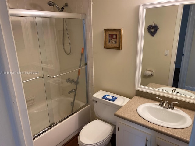 full bathroom with combined bath / shower with glass door, toilet, and vanity