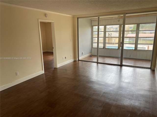 spare room with a textured ceiling, crown molding, and dark wood-type flooring