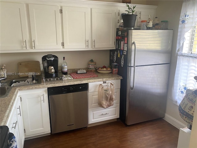 kitchen with light stone counters, dark hardwood / wood-style flooring, white cabinets, and appliances with stainless steel finishes