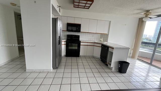 kitchen featuring ceiling fan, light tile patterned flooring, tasteful backsplash, white cabinetry, and black appliances