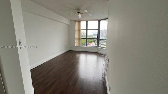 unfurnished room featuring ceiling fan, dark wood-type flooring, and a textured ceiling