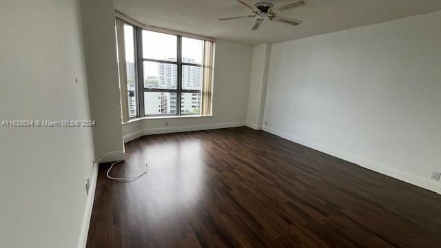 empty room featuring a textured ceiling, dark hardwood / wood-style flooring, and ceiling fan