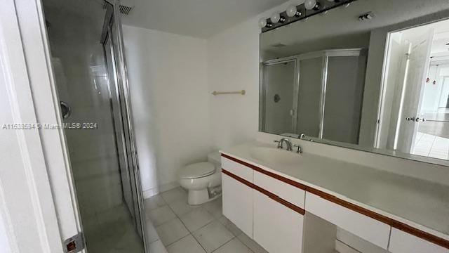 bathroom with a shower with shower door, vanity, tile patterned flooring, and toilet