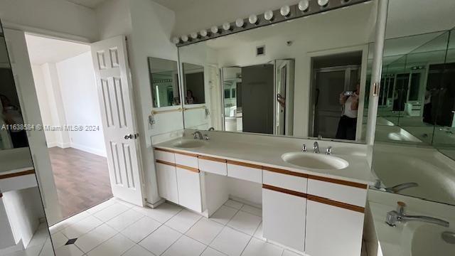 bathroom with double sink vanity, a tub, and tile patterned floors