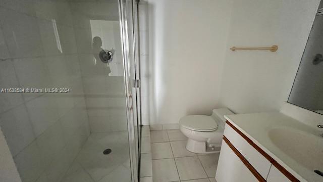 bathroom featuring tile patterned floors, vanity, toilet, and tiled shower