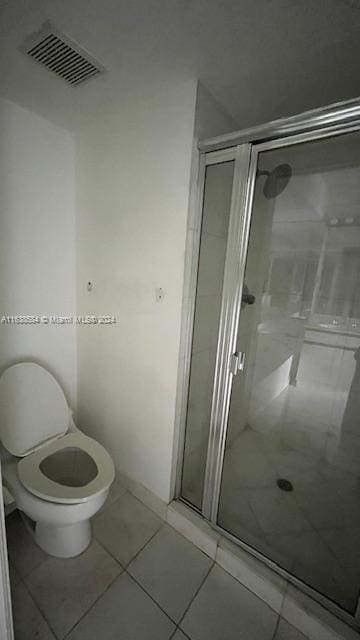 bathroom with a shower with shower door, tile patterned flooring, and toilet