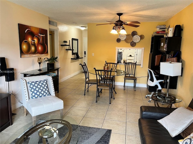 tiled dining space with a textured ceiling and ceiling fan