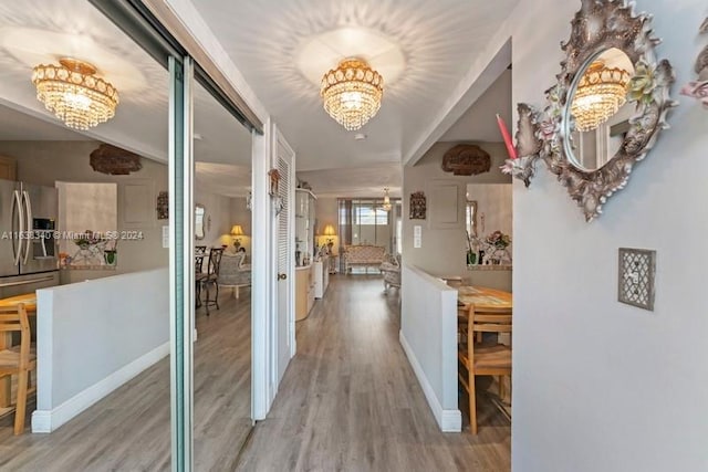 hallway with baseboards, a notable chandelier, and wood finished floors