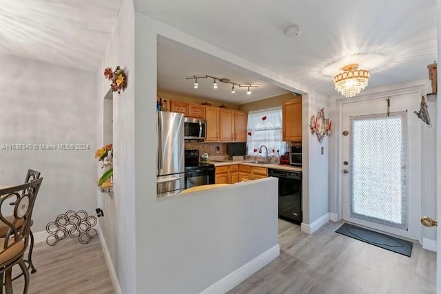 kitchen featuring baseboards, a sink, light wood-style flooring, and black appliances