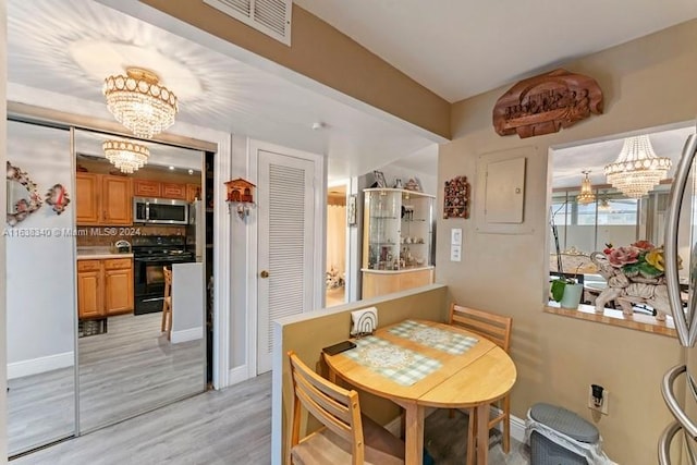 dining room featuring a chandelier, light wood-type flooring, visible vents, and baseboards