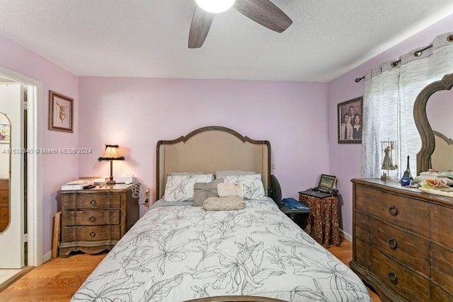 bedroom featuring light wood-style floors, ceiling fan, and a textured ceiling