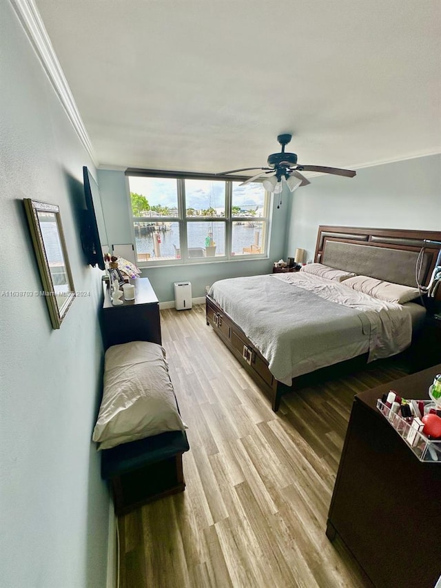 bedroom with ceiling fan, light wood-type flooring, and ornamental molding