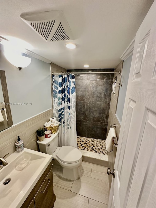 bathroom featuring a shower with curtain, vanity, toilet, and tile walls