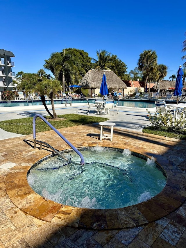 view of property's community with a swimming pool with hot tub