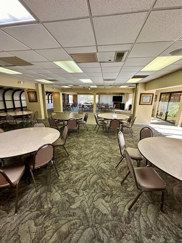 carpeted dining space featuring a paneled ceiling