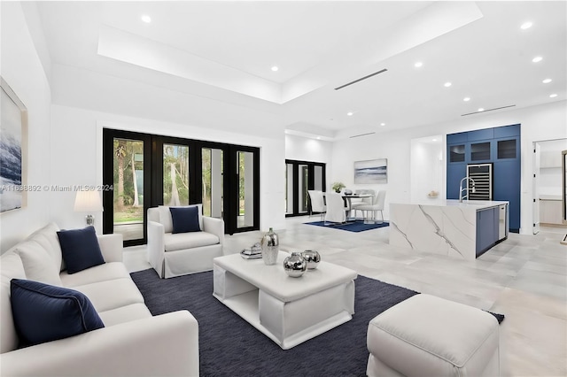 living room featuring a raised ceiling, sink, light tile patterned flooring, and french doors