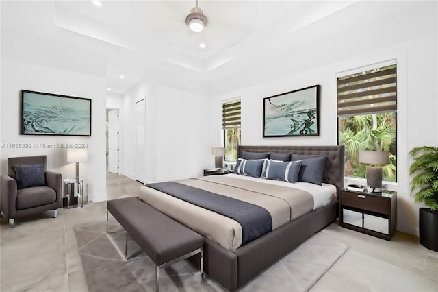 bedroom with ceiling fan, a tray ceiling, and multiple windows