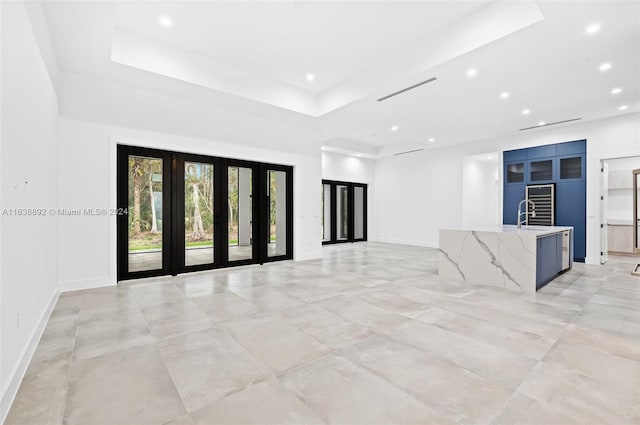 unfurnished living room featuring light tile patterned floors, sink, and a raised ceiling