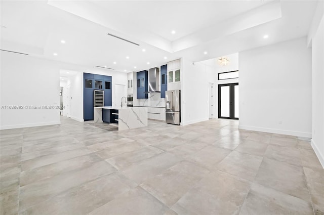 unfurnished living room featuring light tile patterned flooring and a raised ceiling