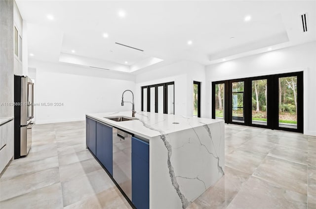 kitchen with a raised ceiling, sink, an island with sink, and light tile patterned floors