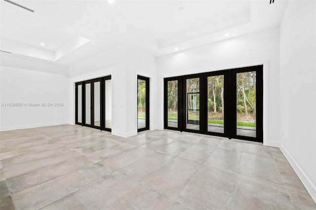 spare room featuring french doors, light tile patterned floors, and a raised ceiling