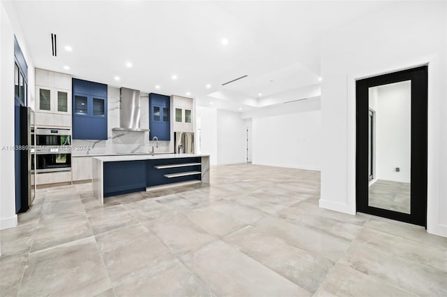 kitchen featuring tasteful backsplash, stainless steel appliances, light tile patterned floors, wall chimney range hood, and a kitchen island