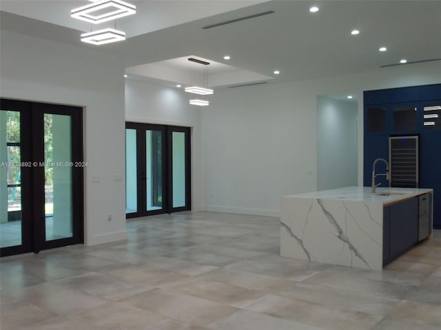 unfurnished room with sink, french doors, light tile patterned flooring, and a tray ceiling