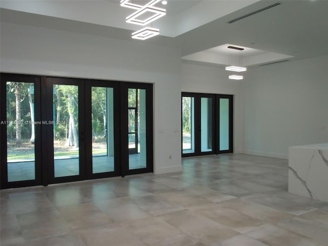 empty room featuring light tile patterned flooring, a raised ceiling, and french doors