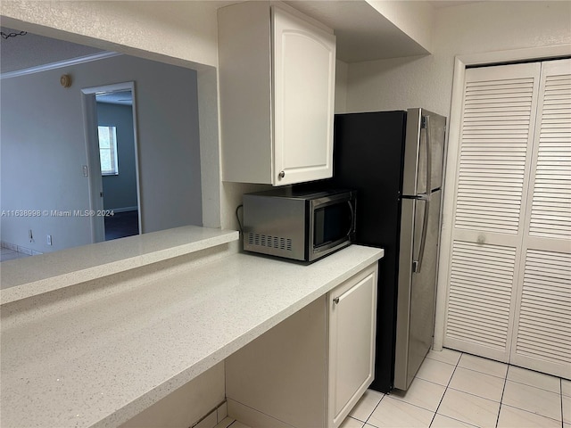 kitchen with stainless steel appliances, light tile patterned flooring, and white cabinets