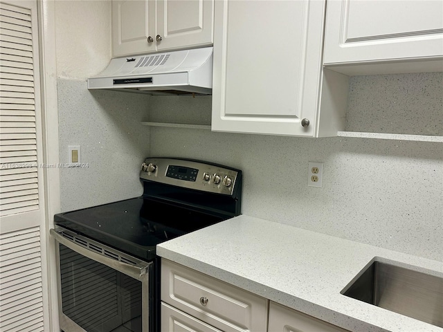 kitchen with stainless steel range with electric stovetop, white cabinets, and backsplash