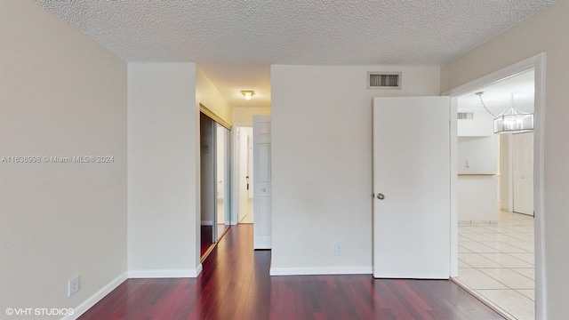 empty room with wood-type flooring and a textured ceiling