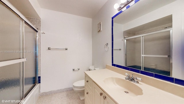 full bathroom featuring vanity, combined bath / shower with glass door, toilet, and tile patterned floors