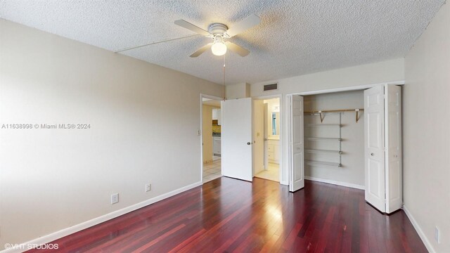 unfurnished bedroom featuring a textured ceiling, dark hardwood / wood-style floors, a closet, and ceiling fan