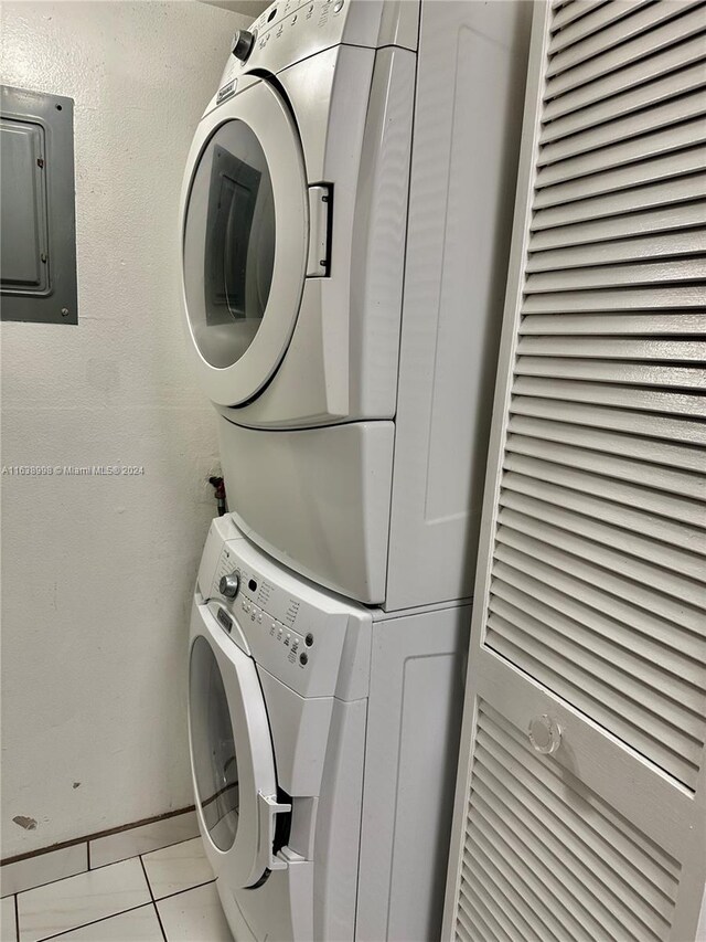 laundry room featuring stacked washer / drying machine and light tile patterned flooring