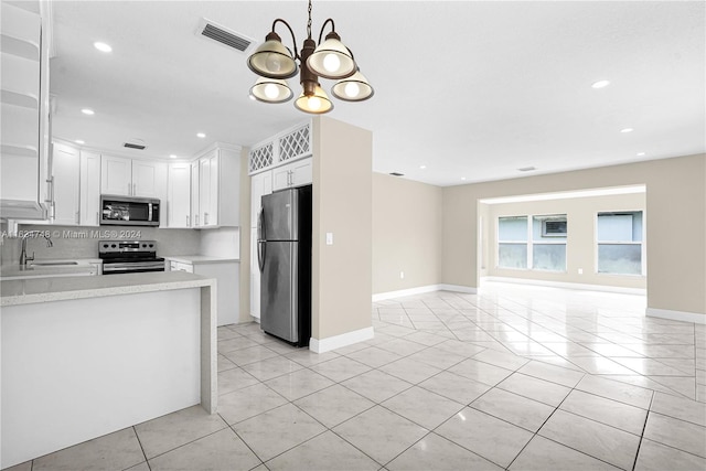 kitchen with stainless steel appliances, decorative backsplash, sink, white cabinetry, and a chandelier