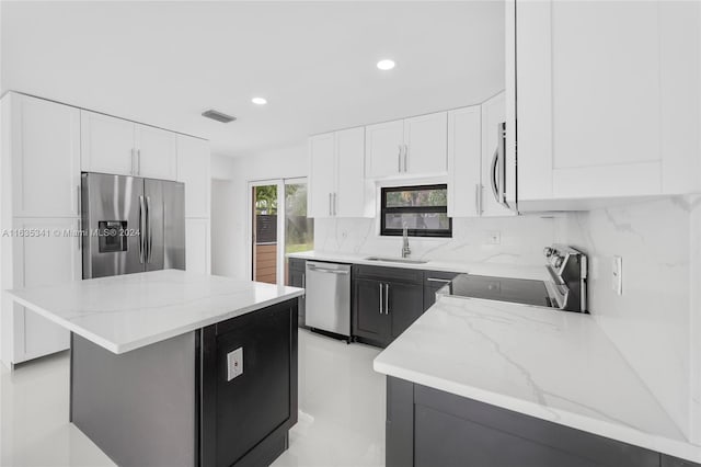 kitchen featuring tasteful backsplash, stainless steel appliances, light stone counters, sink, and white cabinets